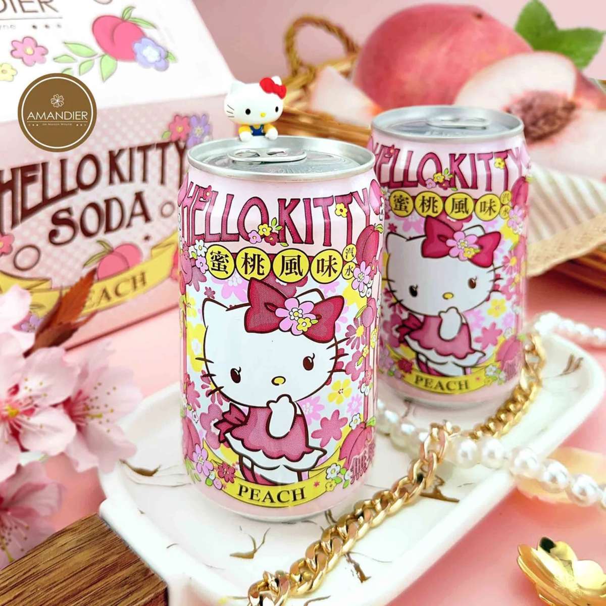 Two cans of Hello Kitty peach soda on a decorative tray with peaches and flowers.