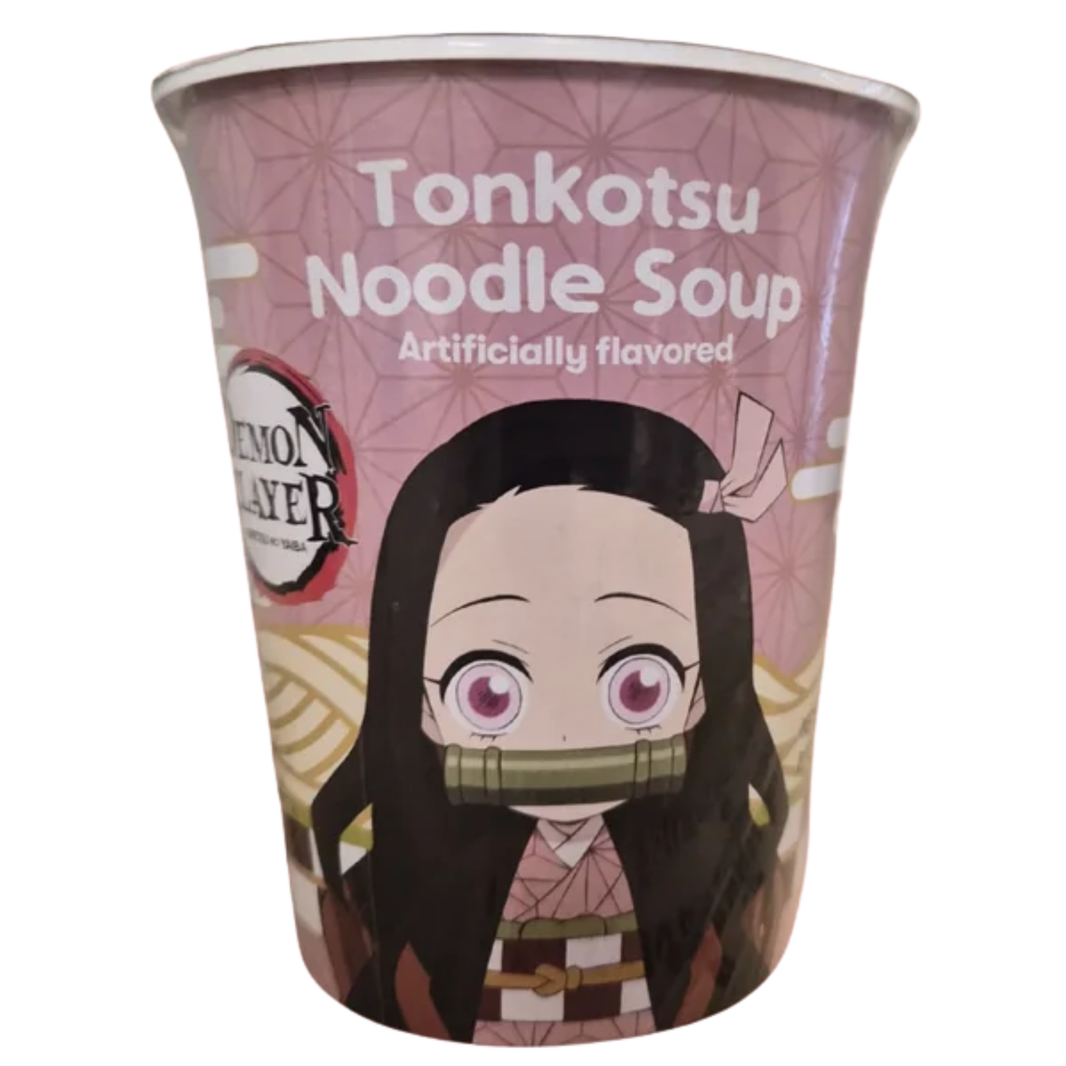 A pink cup of instant soup featuring Demon Slayer theme packaging labeled "Tonkotsu Noodle Soup - Artificially flavored" at the top. Centered on the front is an anime illustration of Nezuko Kamado with her large pink eyes, pink ribbon, and bamboo muzzle, set against a pink hemp-leaf geometric pattern background. The "Demon Slayer: Kimetsu no Yaiba" logo is printed on the left side.