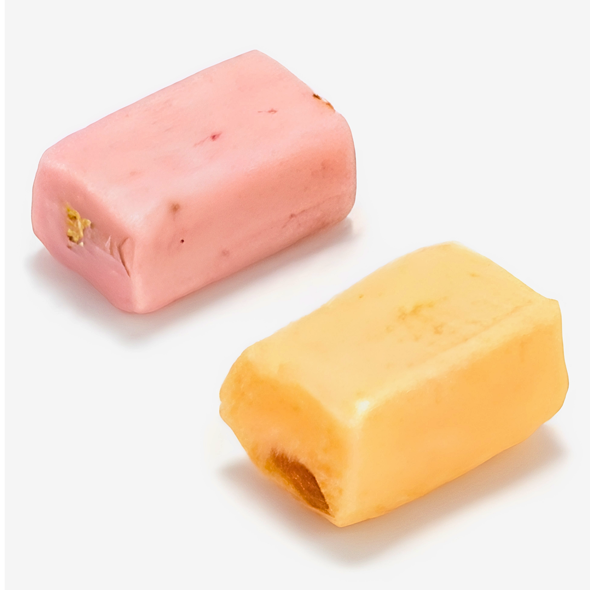 Two rectangular wax melts or soap bars, one pink with tiny embedded flecks and one pale yellow.